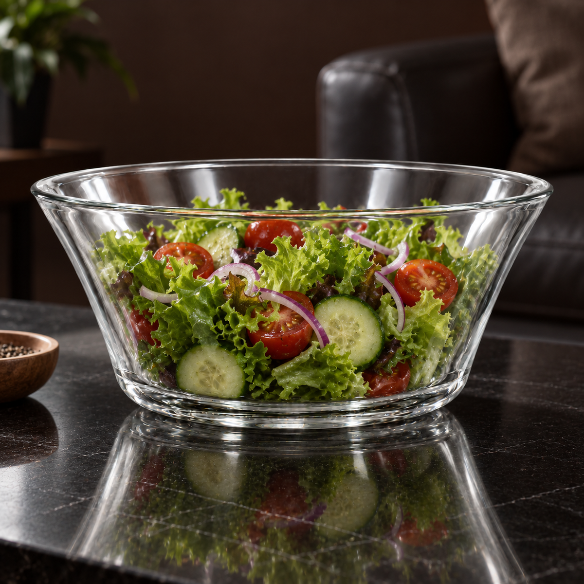 Clear glass bowl with fresh salad on a black table