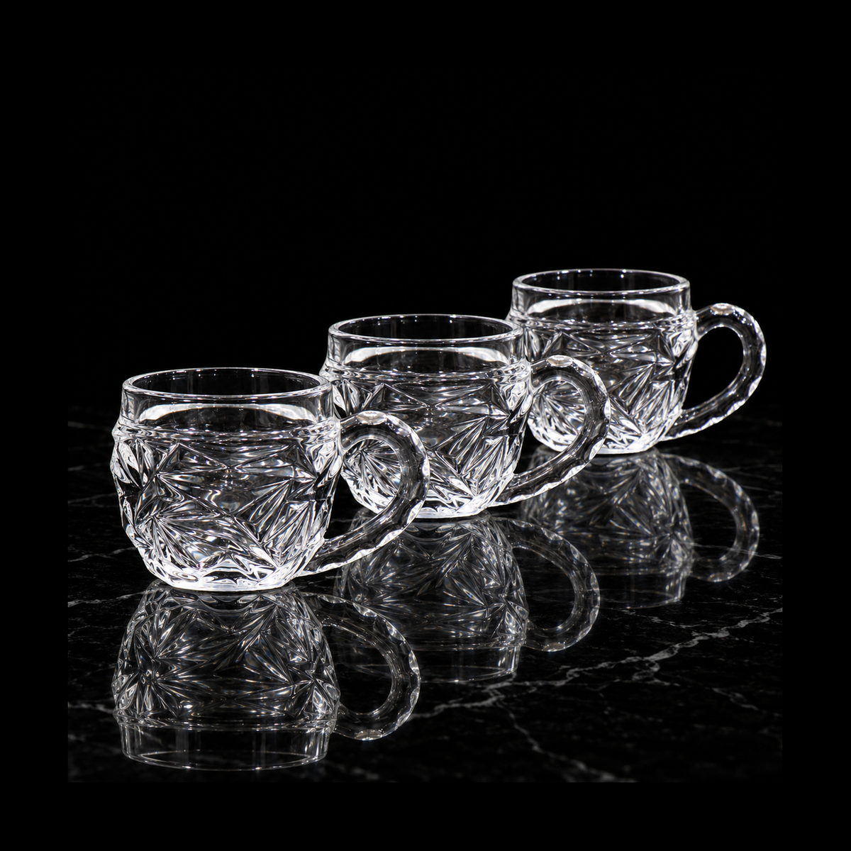 Starburst-cut glass tea cups on black marble