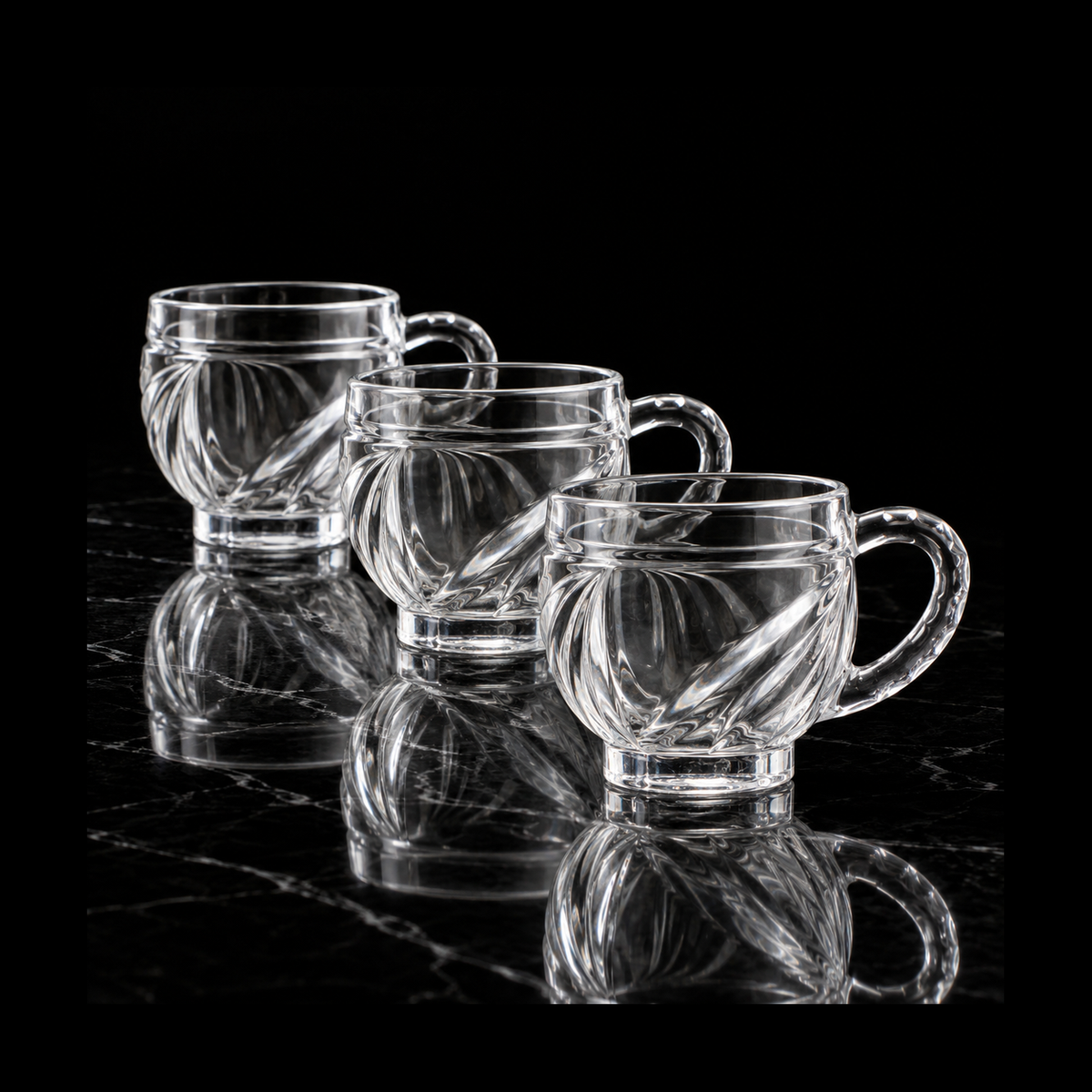 Swirl-cut glass tea cups on black marble