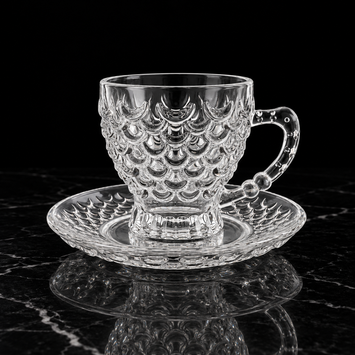 Fish scale glass tea cup and saucer on black marble