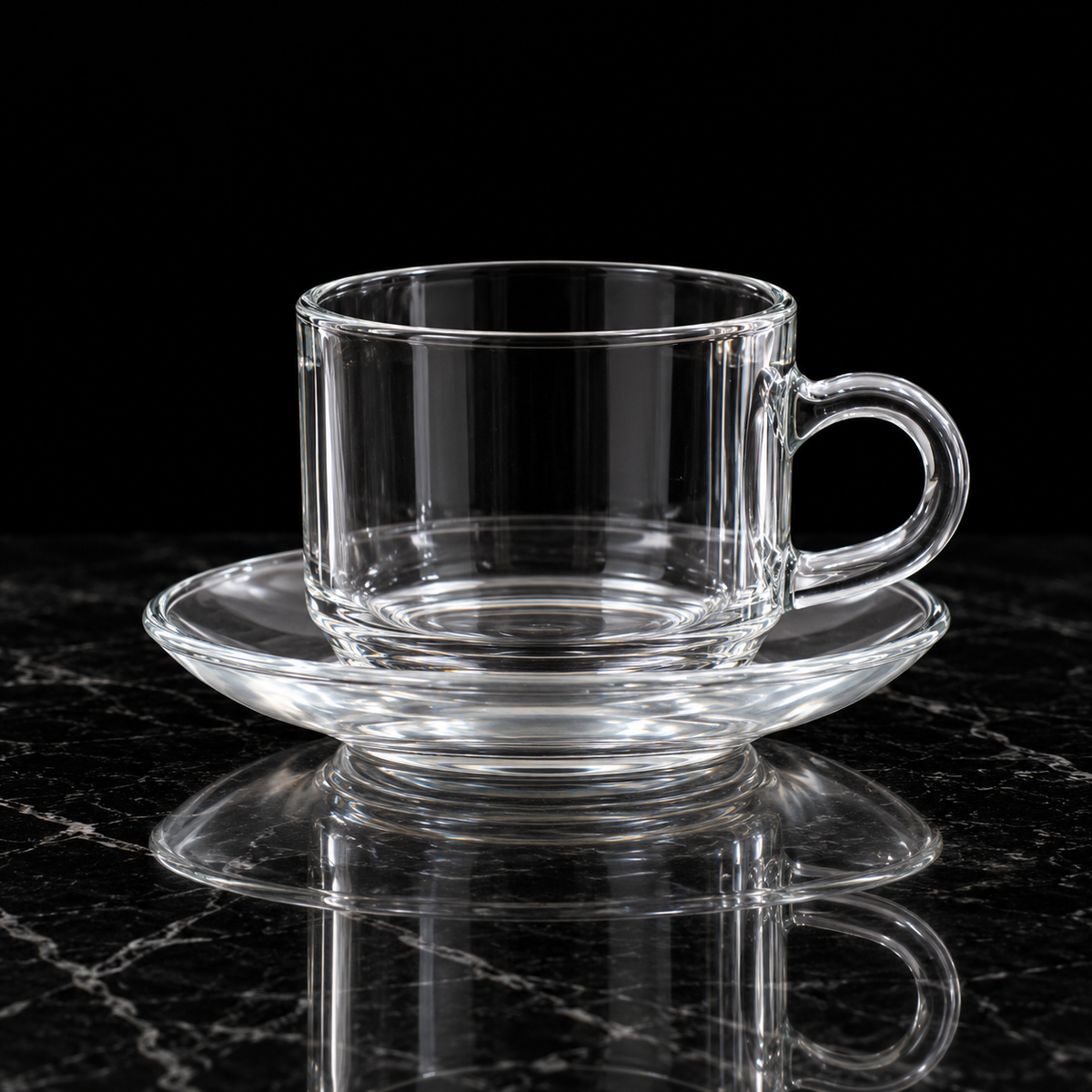 Clear glass tea cup and saucer on black marble