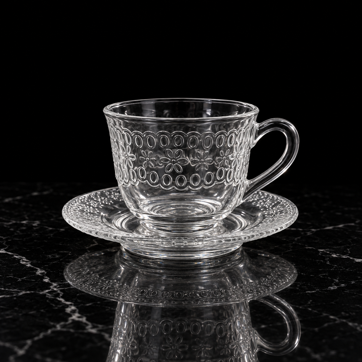 Embossed floral glass tea cup and saucer on black marble