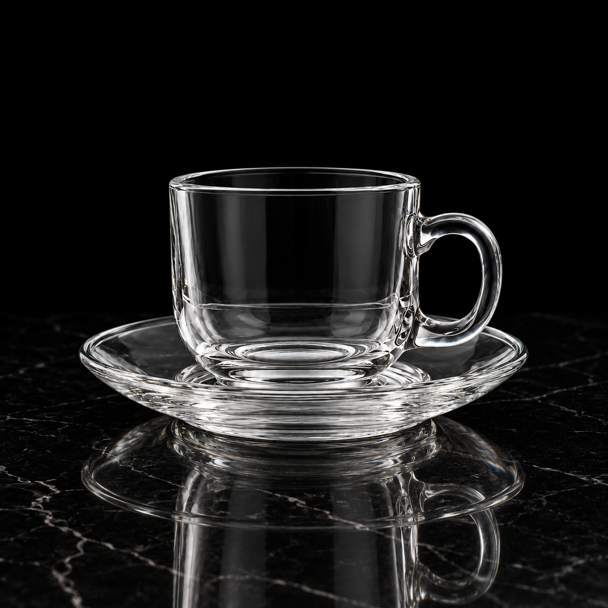 Clear glass tea cup and saucer on black marble