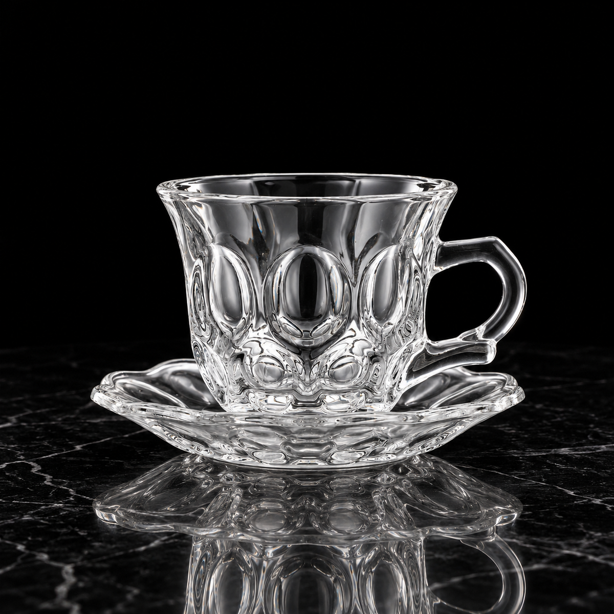 Oval bubble glass tea cup and saucer on black marble