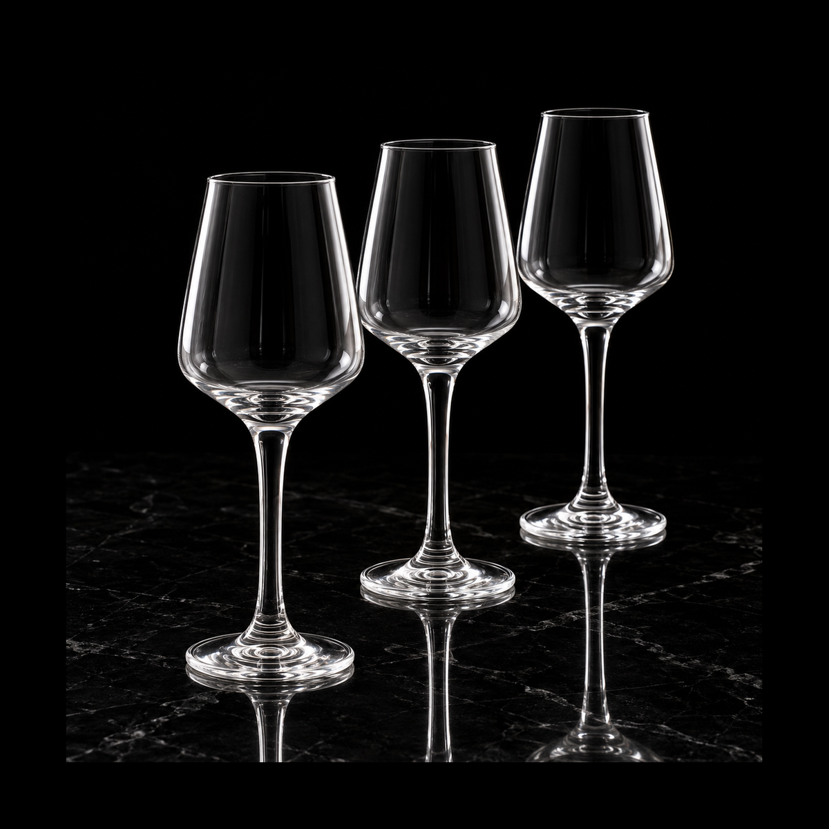 Clear tulip stemmed glasses on black marble